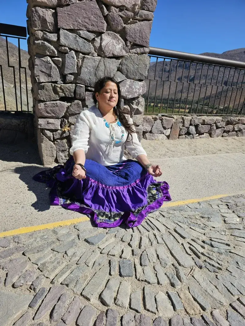 Alicia Guevara, fundadora de KenAly, sentada en meditación frente a un muro de piedra
