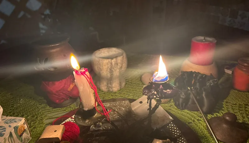 Velas encendidas y objetos de ritual sobre una superficie verde